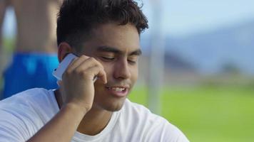 tiener basketbalspeler praten op mobiele telefoon op buitenbaan video