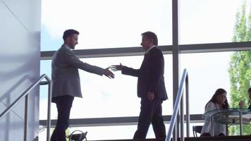 zakenmensen ontmoeten elkaar en schudden elkaar de hand boven aan de trap video