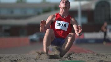 piste athlète atterrissant dans le sable sur saut en longueur en super ralenti, tourné sur fantôme flex 4k