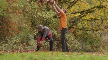 dos niños en otoño lanzando hojas en cámara lenta video