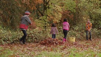Group of kids in Fall raking leaves
