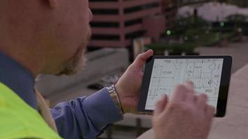 Construction supervisor looking at plans on digital tablet video