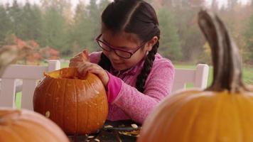 junges Mädchen, das Kürbis für Halloween schnitzt video