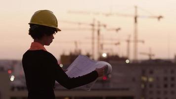 Architect holding plans looking at construction site at sunset video