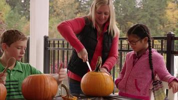 Mom and kids carving pumpkins for Halloween video