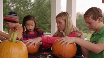 Mom and kids carving pumpkins for Halloween video