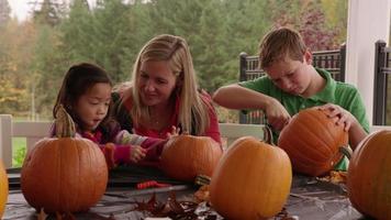 Mom and kids carving pumpkins for Halloween video