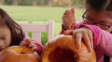 Young girls carving pumpkin for Halloween