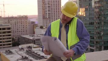 bouwmanager op het dak met behulp van plannen kijken
