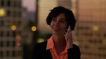 Mujer hablando por teléfono celular por la noche en la ciudad