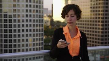 Businesswoman using cell phone on rooftop in city