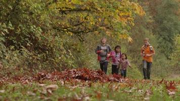 Group of kids in Fall running to pile of leaves