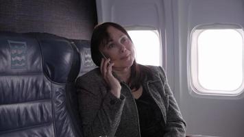 donna d'affari che parla al cellulare in aereo