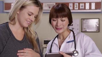 Doctor and patient look at digital tablet together video