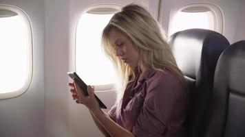 Young woman using digital tablet on airplane flight video