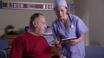 Patient and doctor look at digital tablet together video