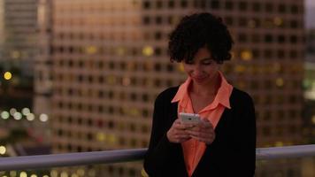 Mujer con teléfono celular por la noche en la ciudad video