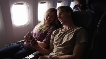 Couple taking selfies with mobile phone on airplane