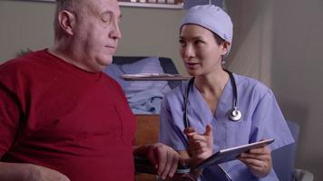 Patient and doctor look at digital tablet together video