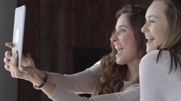 två unga kvinnor på café tar selfies tillsammans med den digitala surfplattan video