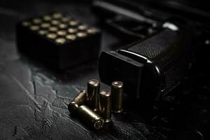 Pistol with cartridges on black concrete table photo