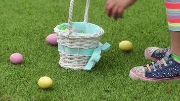 niña recogiendo huevos de pascua en el césped y ponerlos en la canasta video