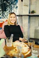 Impresionante chica sentada en una silla en el café y sonríe