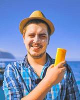 Chico poniéndose loción de protección solar en la cara. foto