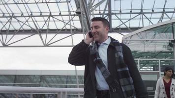 Businessman walking and talking on cell phone at airport video
