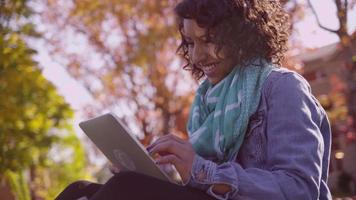 College student on campus in fall using digital tablet video