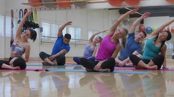 Group of men and women sitting on floor doing yoga at studio video
