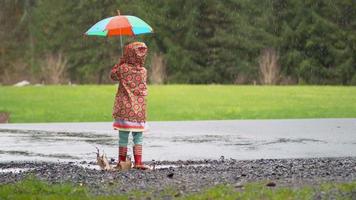 junges Mädchen mit Regenschirm, das im Regen spielt, Zeitlupe, aufgenommen mit Phantomflex 4k video