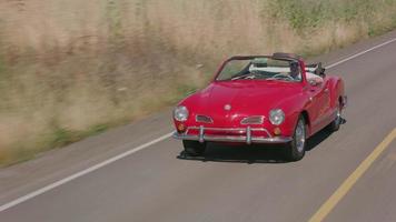Tracking shot of man driving classic convertible car on country road.  Fully released for commercial use. video