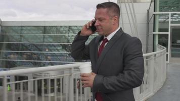 Businessman walking and talking on cell phone at airport video