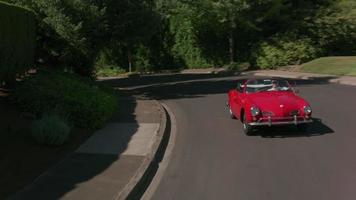 tracking shot van een man die een klassieke cabriolet door de buurt rijdt. volledig vrijgegeven voor commercieel gebruik. video