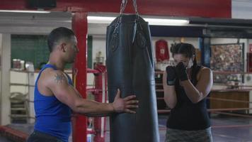 Woman and trainer working out at boxing gym video