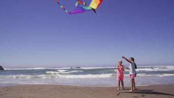 deux jeunes filles jouant avec un cerf-volant à la plage video