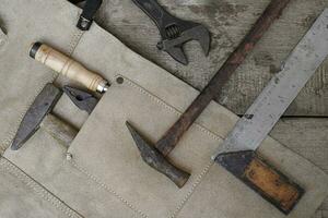 Collection of woodworking old hand tools in leather apron on a rough wooden workbench photo