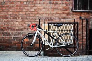 white and black road bike leaning on brown brick wall photo