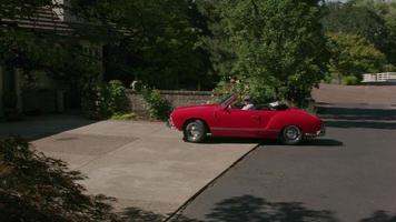 Tracking shot of man pulling out of driveway in classic convertible car.  Fully released for commercial use video