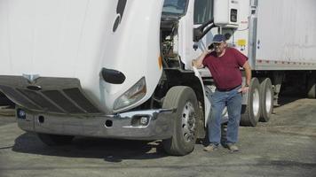 Truck driver with hood open on phone.  Fully released for commercial use. video