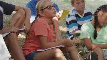 les enfants de l'école en plein air ont une leçon de groupe au bord de l'étang video