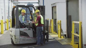 Truck driver and forklift driver talk at shipping facility.  Fully released for commercial use. video