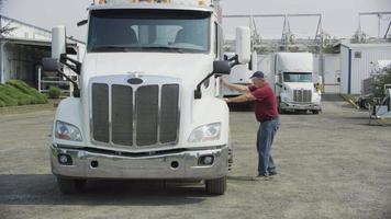 Truck driver getting into semi truck at shipping facility.  Fully released for commercial use. video