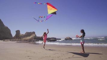 twee jonge meisjes die vliegeren op het strand
