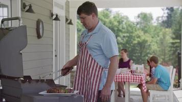 man koken met grill bij barbecue in de achtertuin video