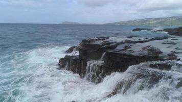 Low angle aerial view of waves crashing cliffs and rocks, Oahu, Hawaii video