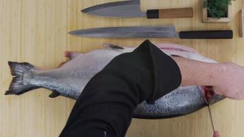 Inquadratura dall'alto dello chef che taglia un grosso salmone