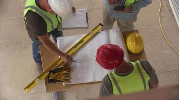 Three construction workers looking over blueprints, overhead shot video
