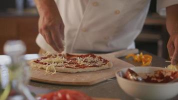 le chef ajoute du fromage mozzarella à la pizza video